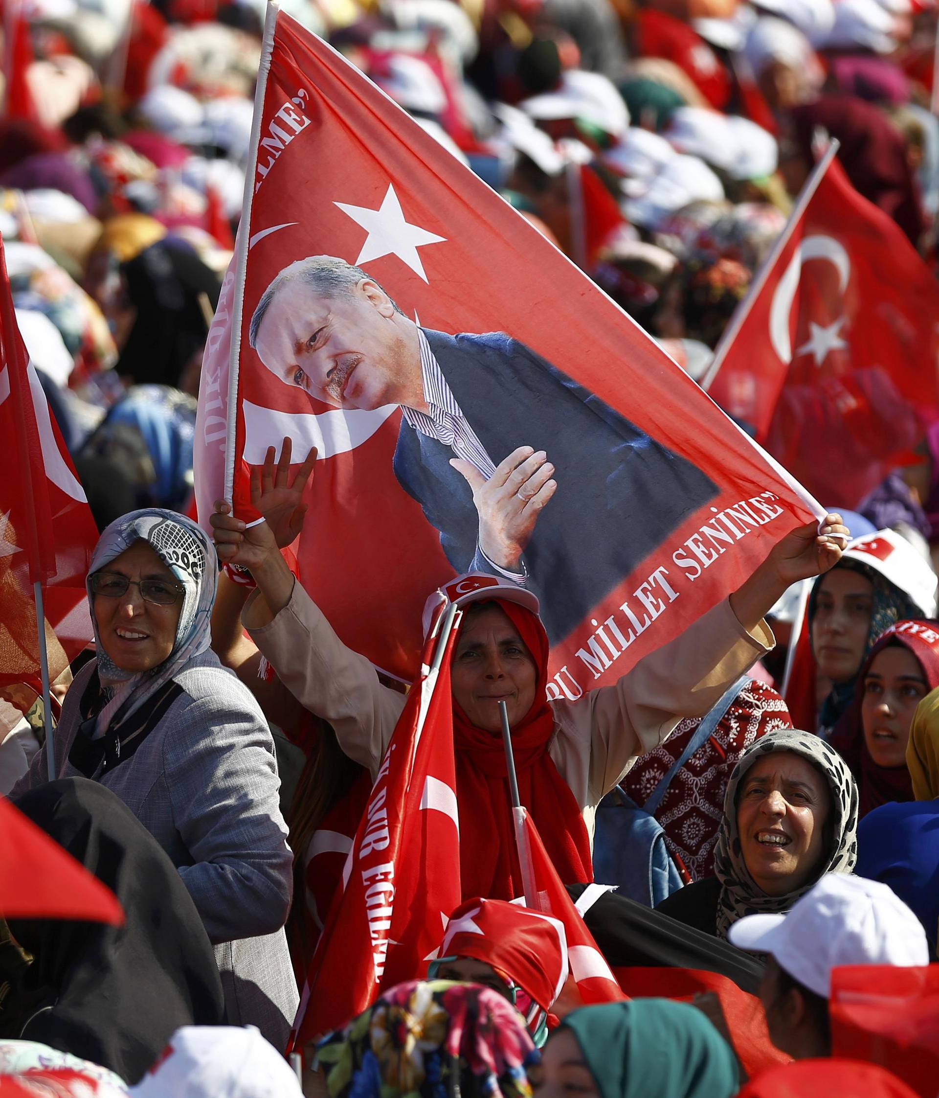 A woman holds flag with the picture of Turkey's President Erdogan during the Democracy and Martyrs Rally in Istanbul