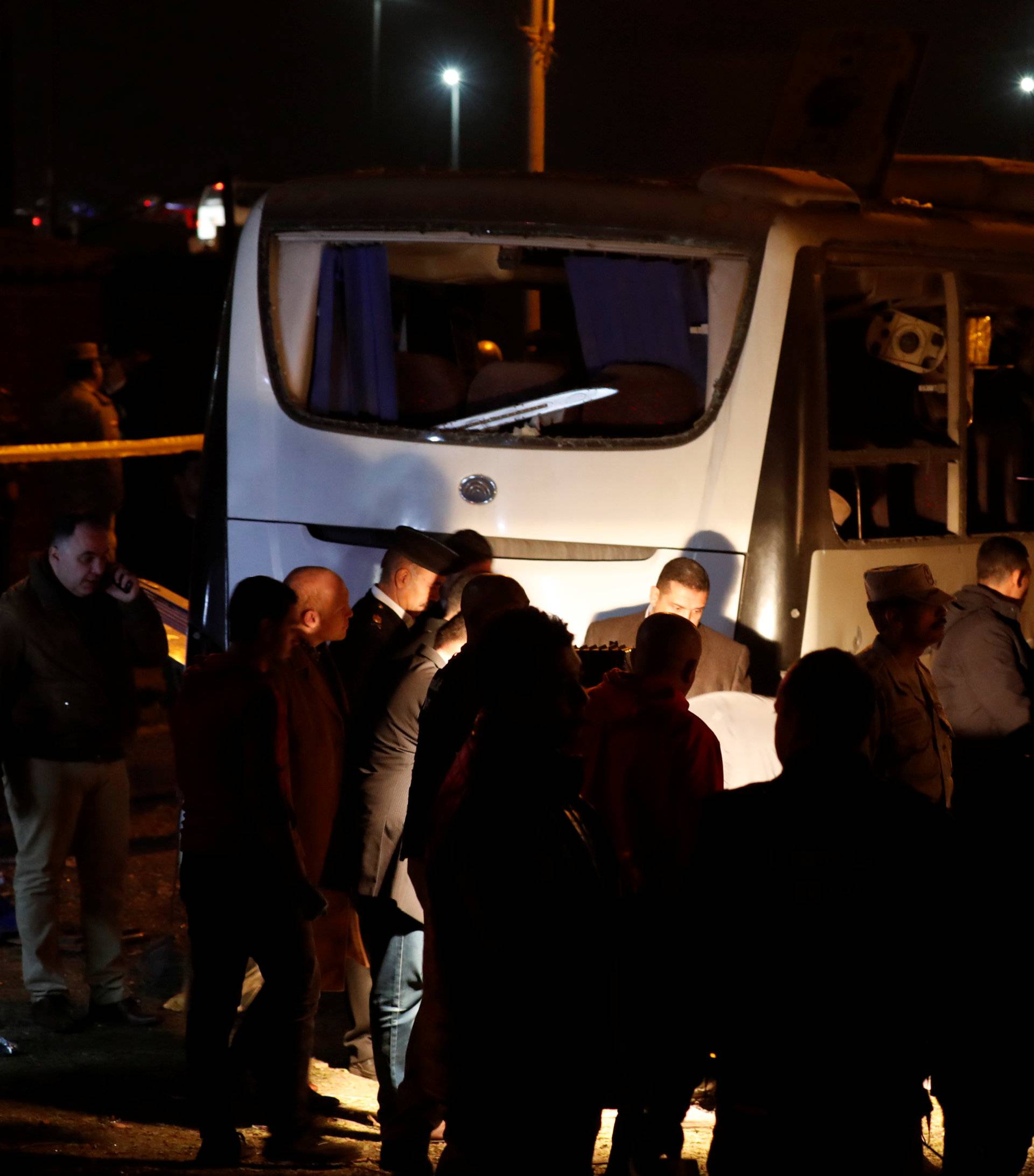 Police officers and officials inspect a scene of a bus blast in Giza