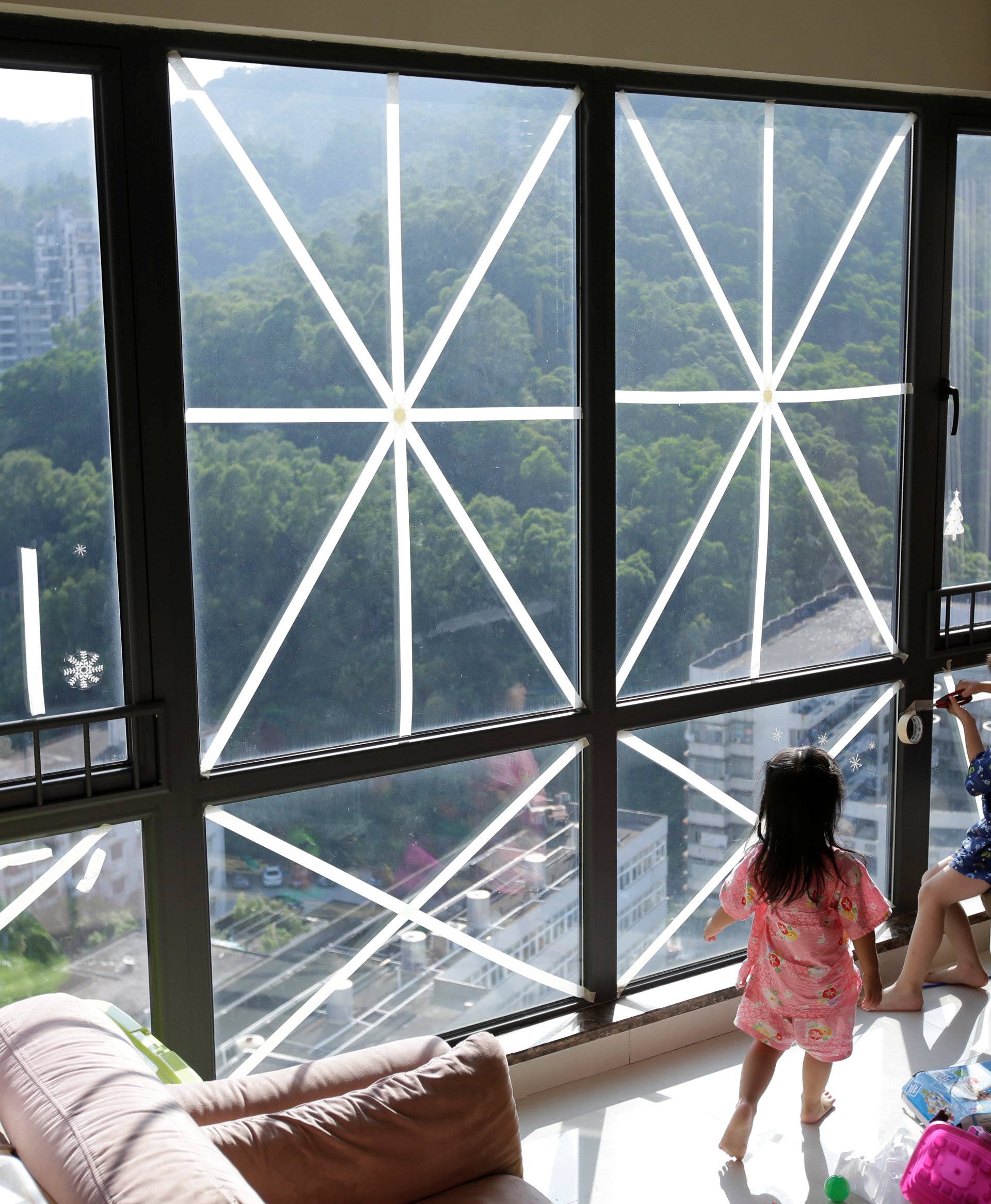 A brother and his sister play at a living room with windows taped in preparation for Typhoon Mangkhut in Shenzhen