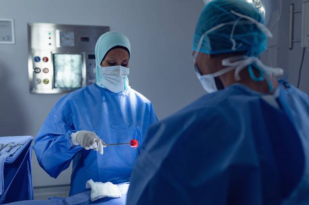 Side view of mixed race female surgeons performing surgery in operation room at hospital