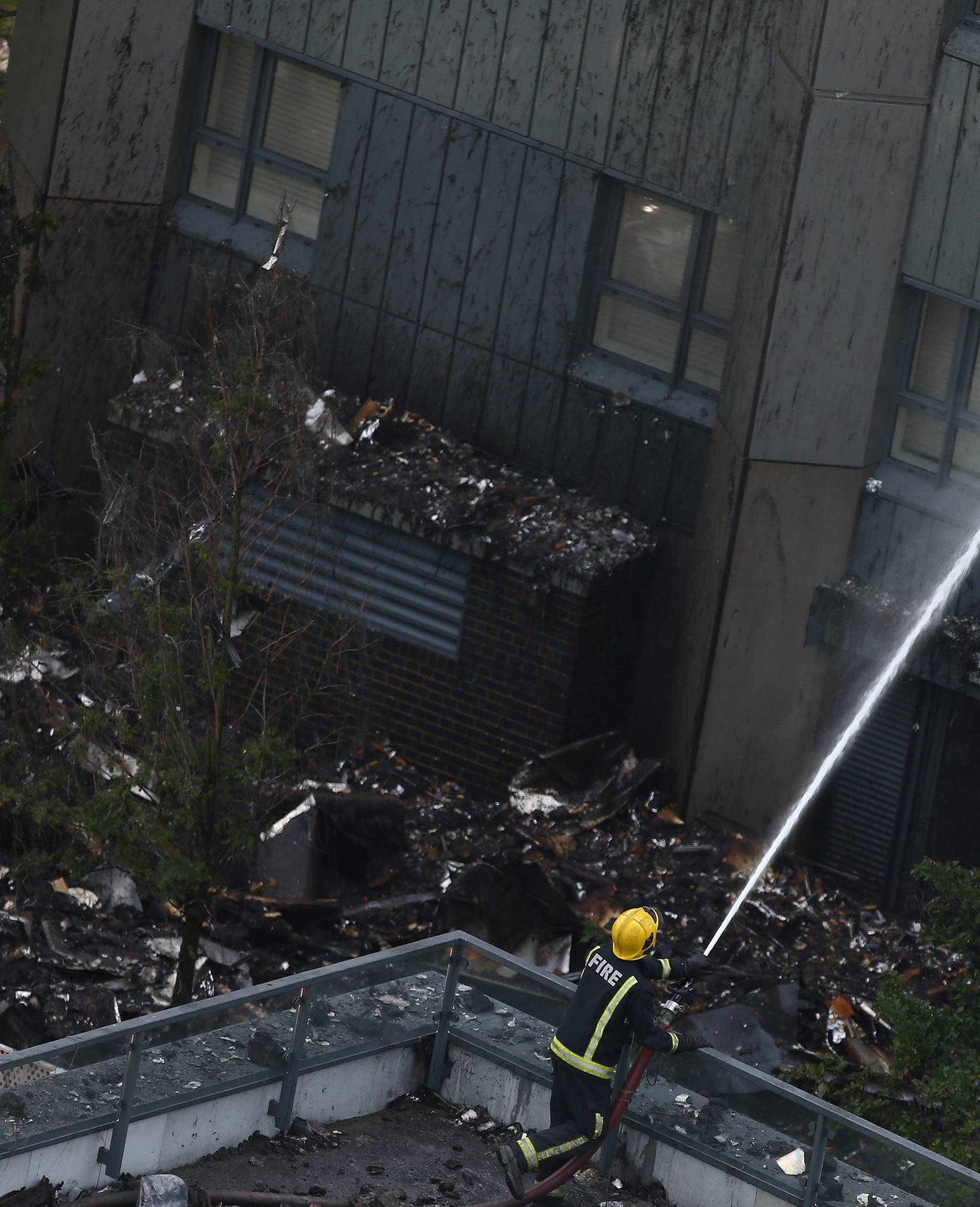 A firefighter directs a jet of water to a tower block severely damaged by a serious fire, in north Kensington, West London