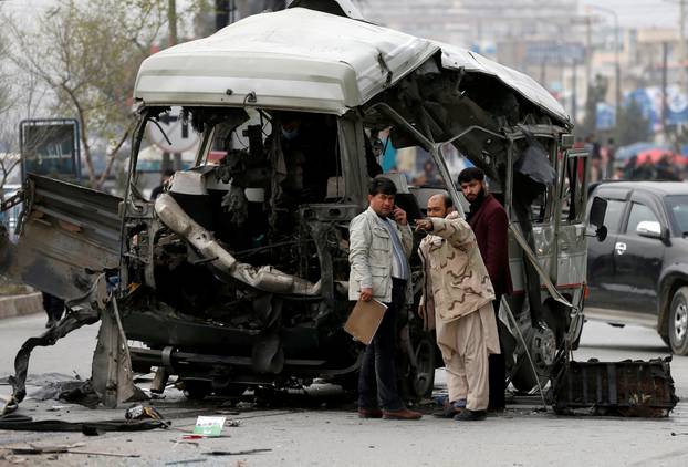 Afghan officials inspect a damaged minibus after a blast in Kabul