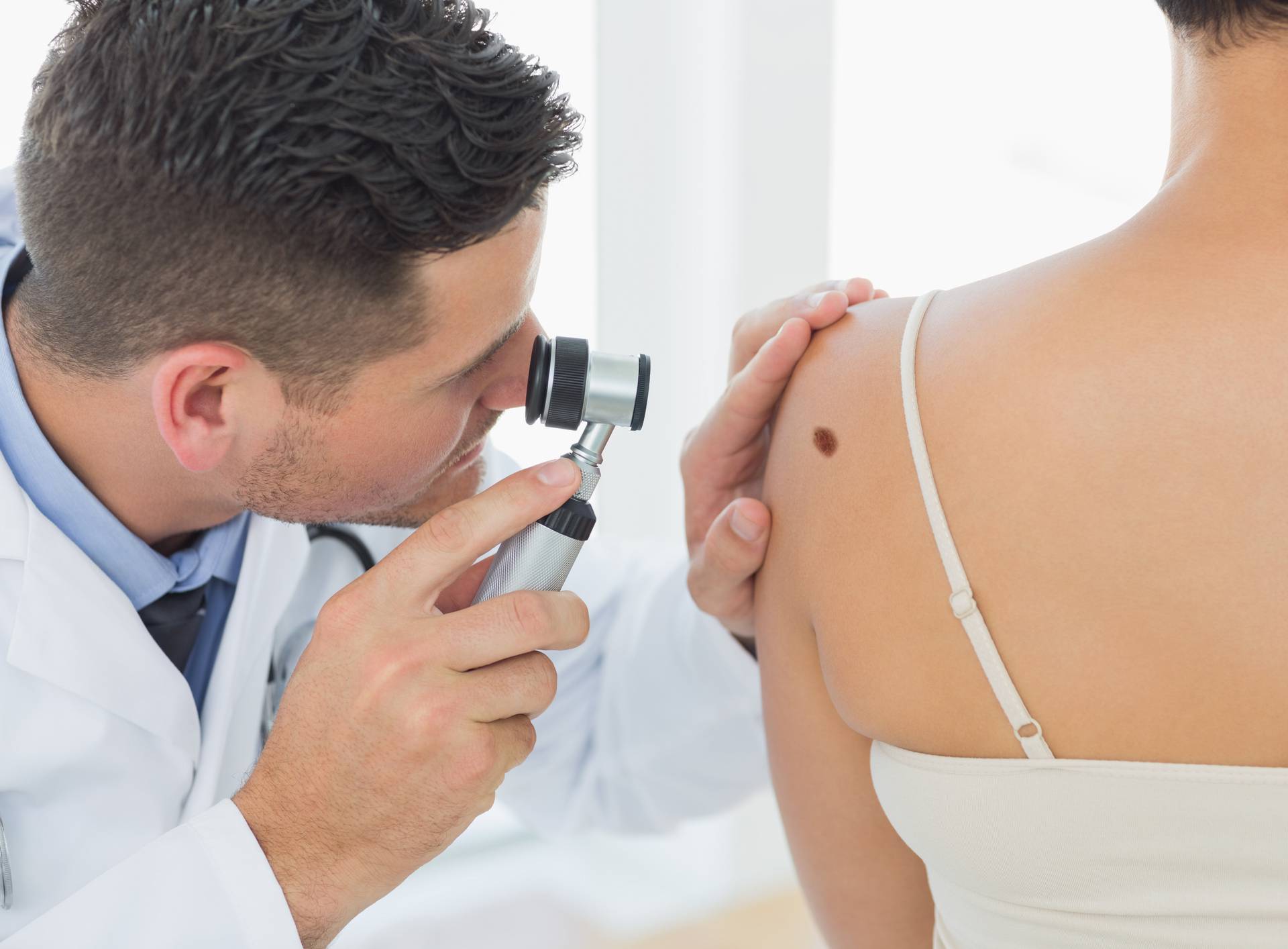 Doctor examining mole on back of woman