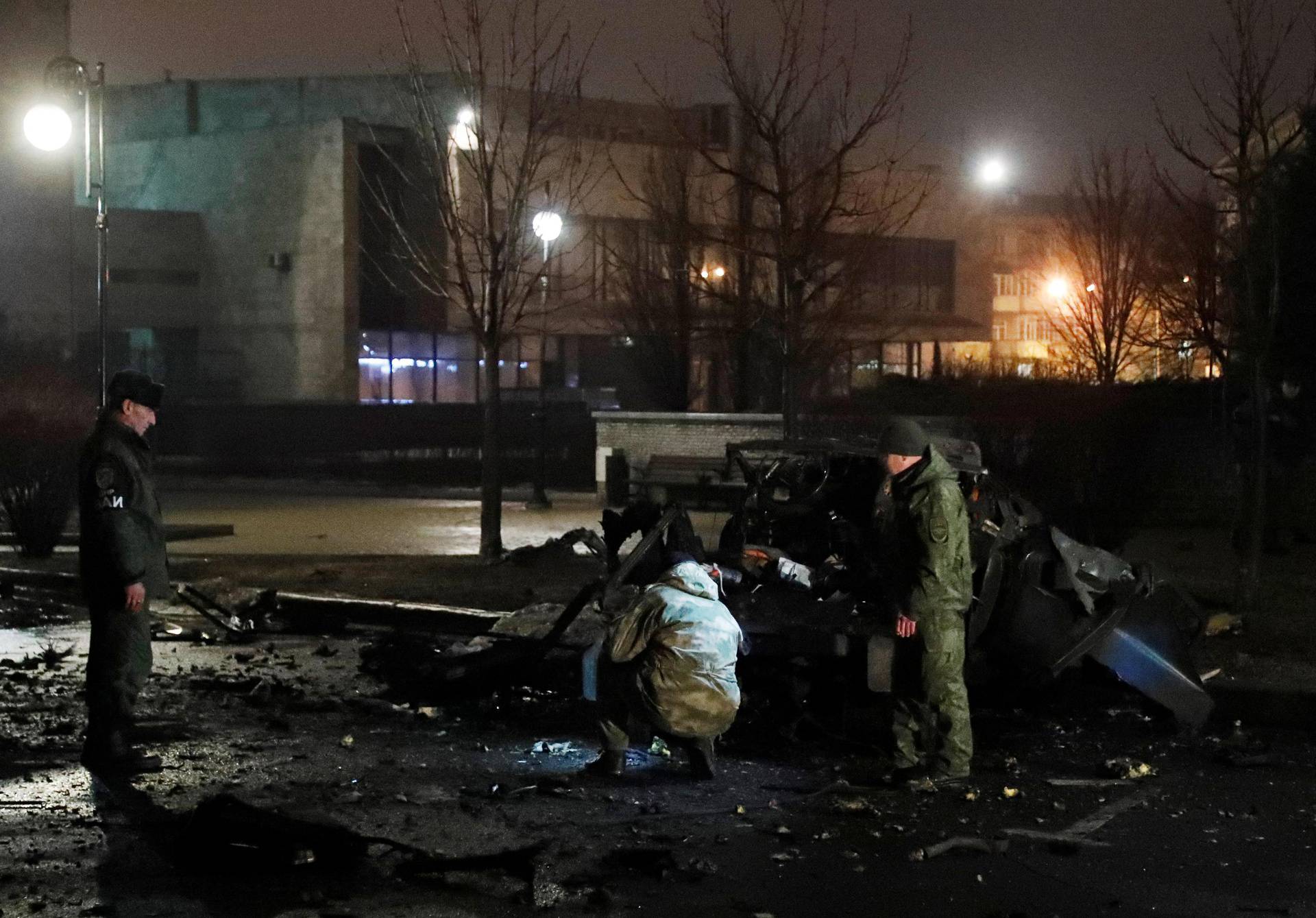 Specialists inspect a wreckage of a car that according to the local authorities was blown up in Donetsk