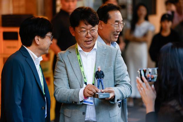 A participant at a dinner between NVIDIA CEO Jensen Huang and executives from South Korean companies shows an action figure of Huang to members of the press outside a restaurant in Taipei