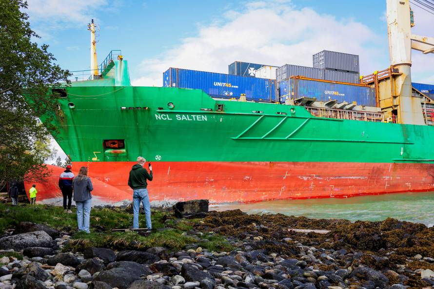 People stand near a container ship, which almost hit a house, in Trondheim