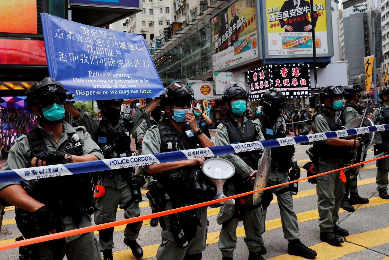 Riot police stand in line as anti-national security law protesters march at the anniversary of Hong Kong's handover to China from Britain in Hong Kong