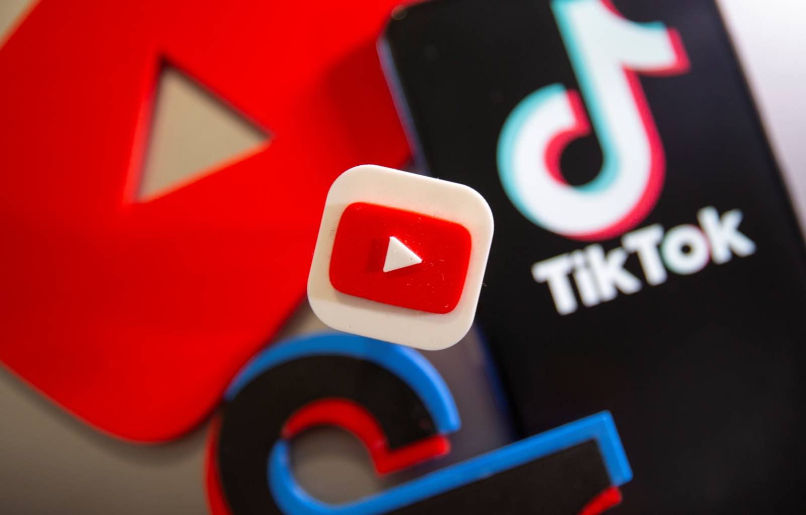 A 3D printed Youtube and Tik Tok logos are seen near smartphone with displayed Tik Tok logo in this illustration taken