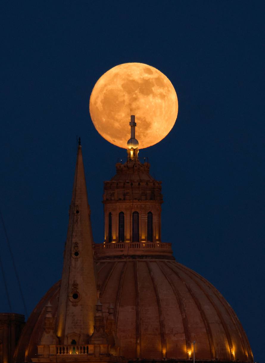 A full moon known as the Strawberry Moon rises behind St Paul's Anglican Cathedral and the Basilica of Our Lady of Mount Carmel in Valletta