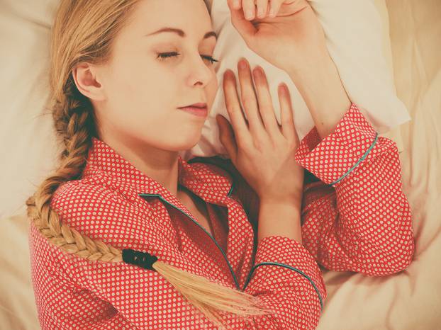 Woman sleeping in bed on the side