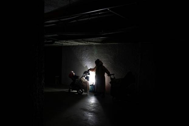 Woman with kids takes shelter inside an underground parking during Russian missile and drone attac k in Kyiv