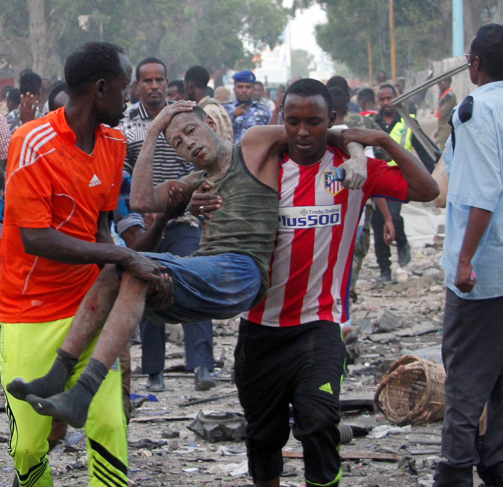 Civilians assist a man injured from a suicide car bombing at the gate of Naso Hablod Two Hotel in Mogadishu