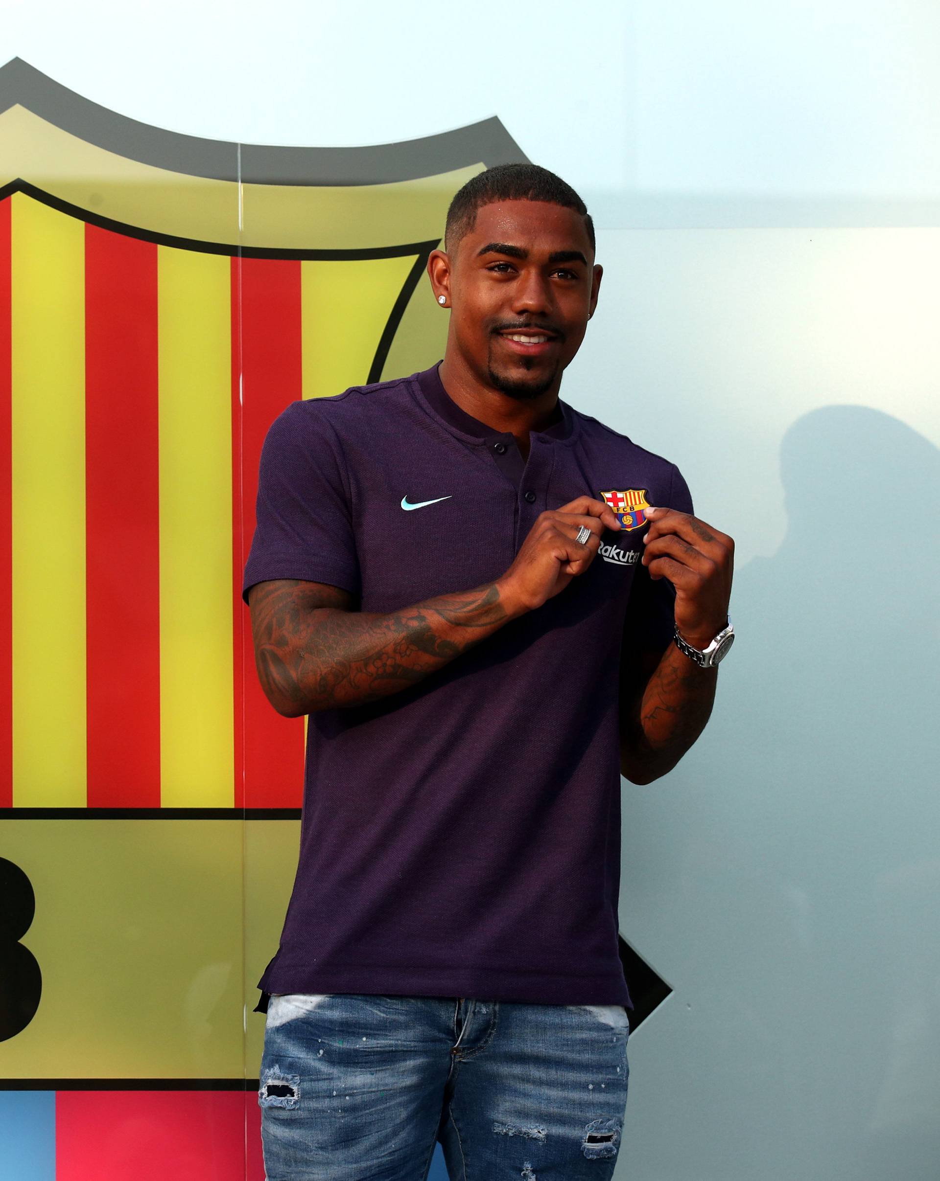 Brazilian soccer player Malcom Filipe Silva de Oliveira poses in front of a FC Barcelona logo at their offices next to Camp Nou stadium in Barcelona