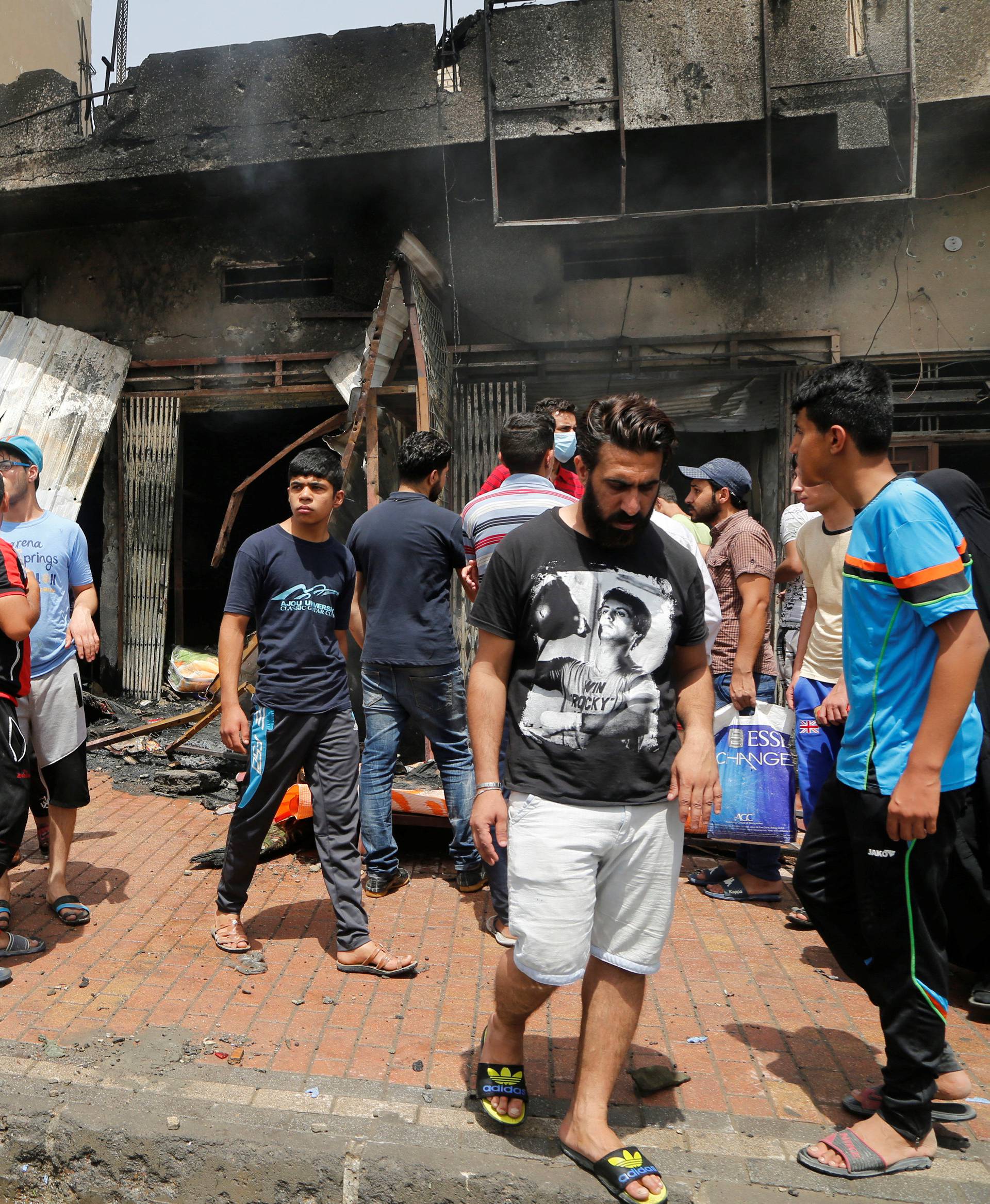 People gather at the scene of a car bomb attack in Baghdad's mainly Shi'ite district of Sadr City