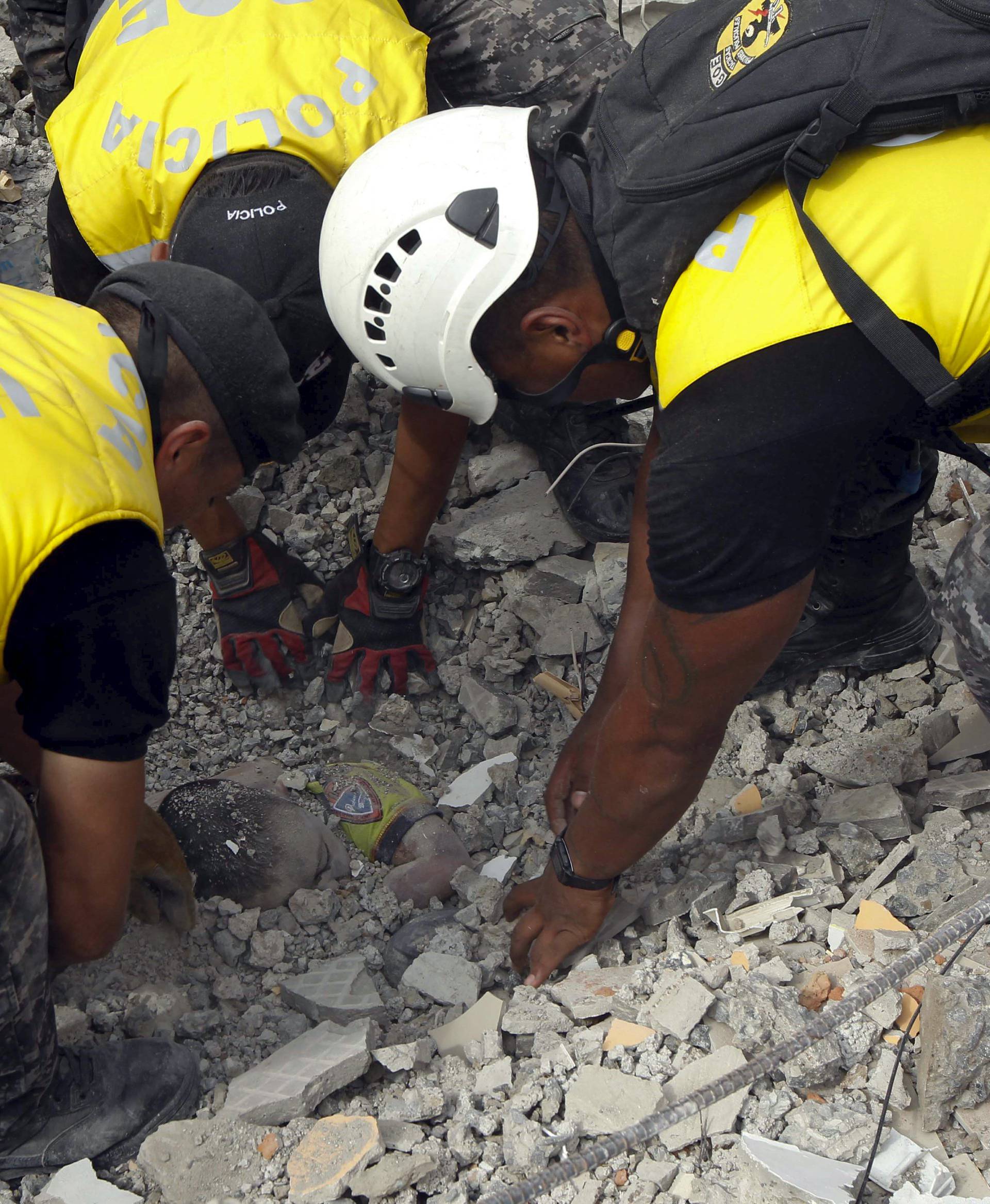 Police officers uncover the body of a victim after an earthquake struck off Ecuador's Pacific coast, at Tarqui neighborhood in Manta