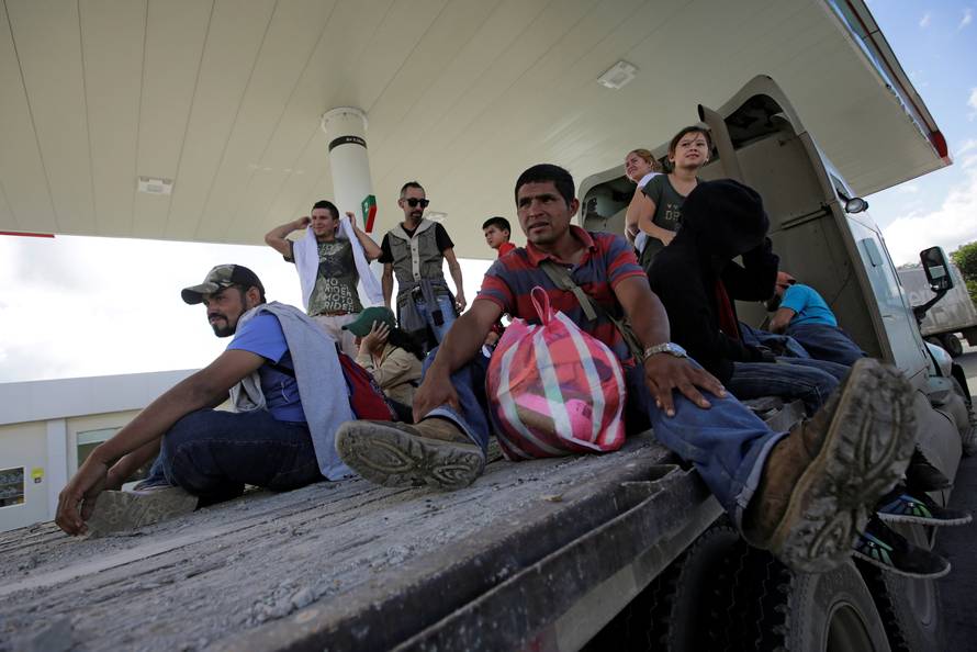 Hondurans, part of a new caravan of migrants travelling towards the United States, sit on a trailer as they hitch a ride in Cucuyagua