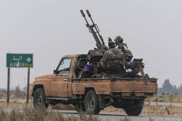 A rebel fighter sits on the back of a vehicle in Homs countryside