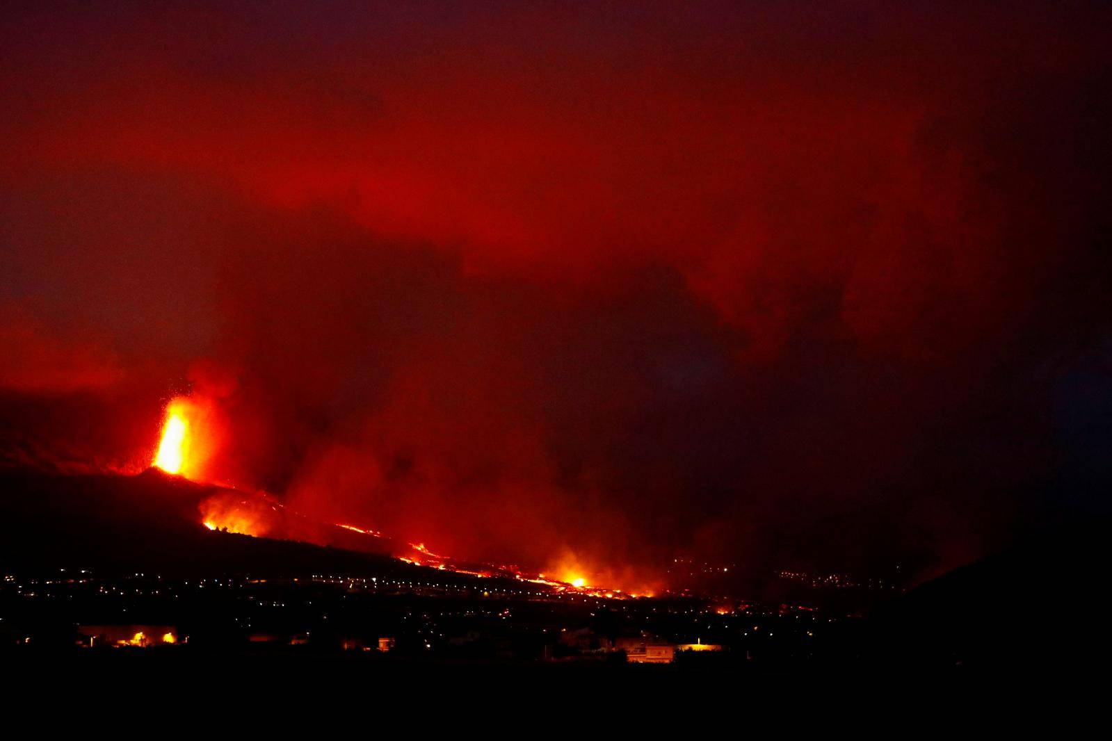 Lava flows behind houses following the eruption of a volcano in Spain