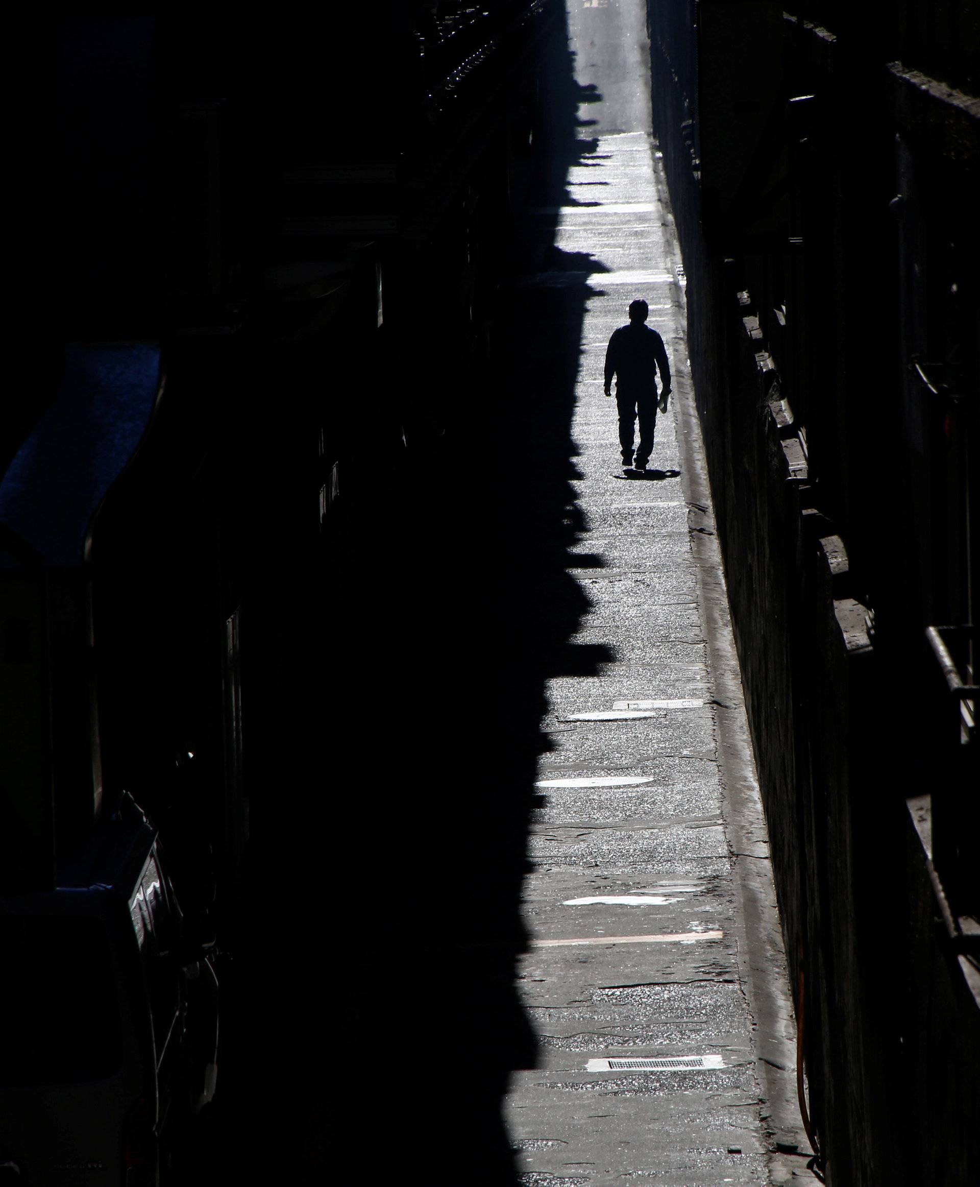 A man walks in a small road between two commercial buildings at a business district in Tokyo