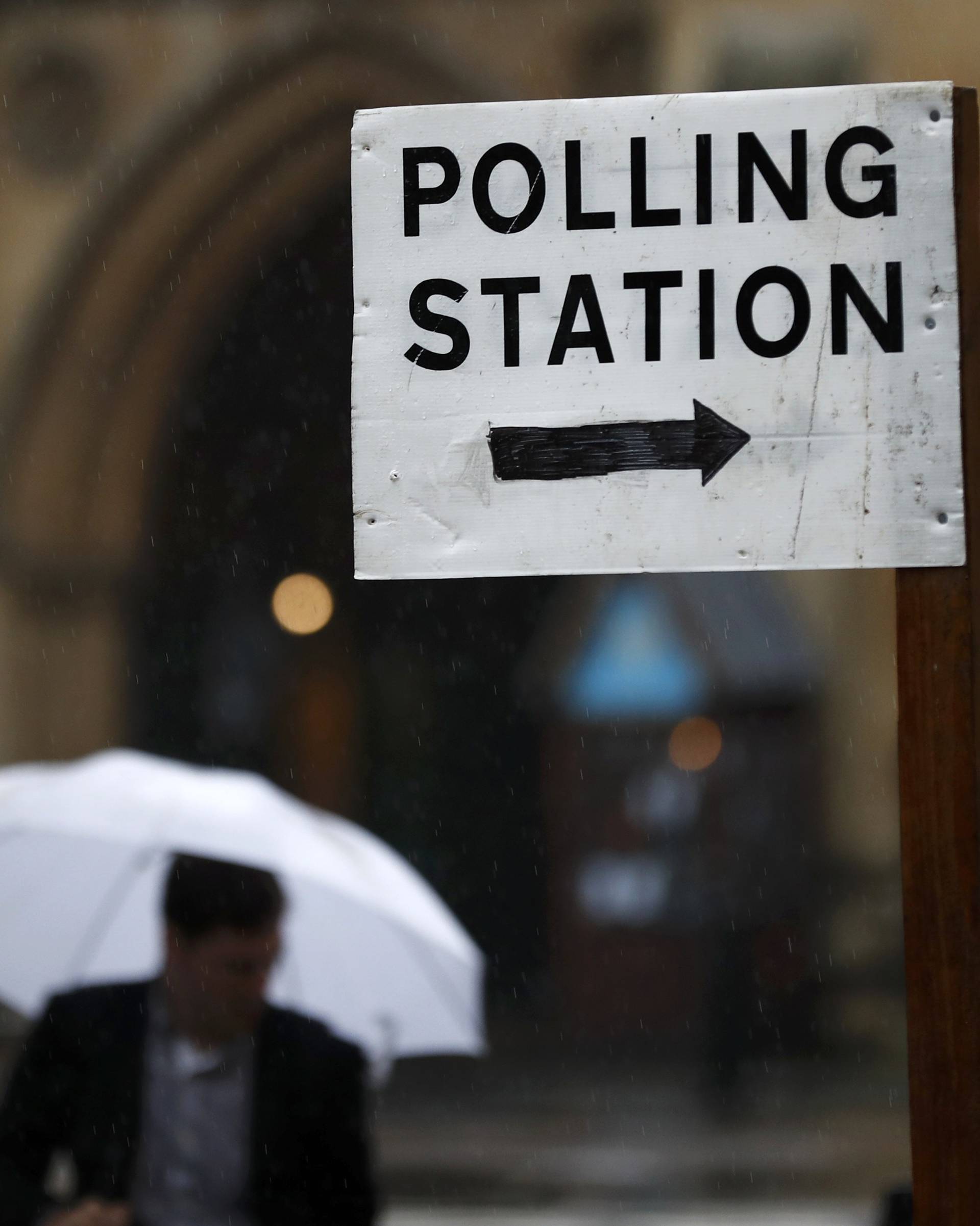 A man carries an umbrella past a polling station for the Referendum on the European Union in central London, Britain
