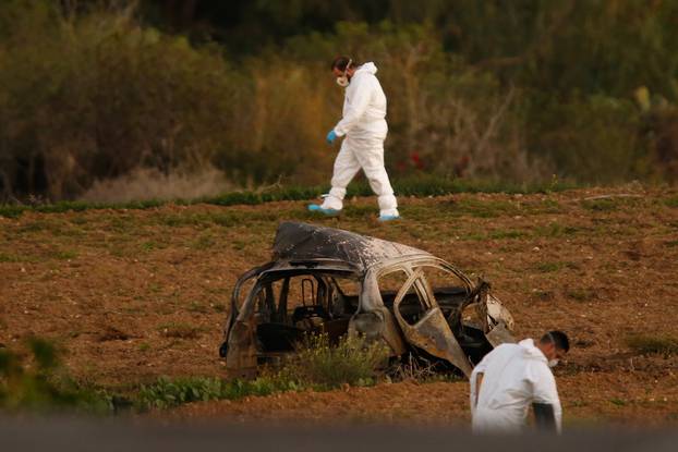 Forensic experts walk in a field after a powerful bomb blew up a car killing investigative journalist Daphne Caruana Galizia in Bidnija