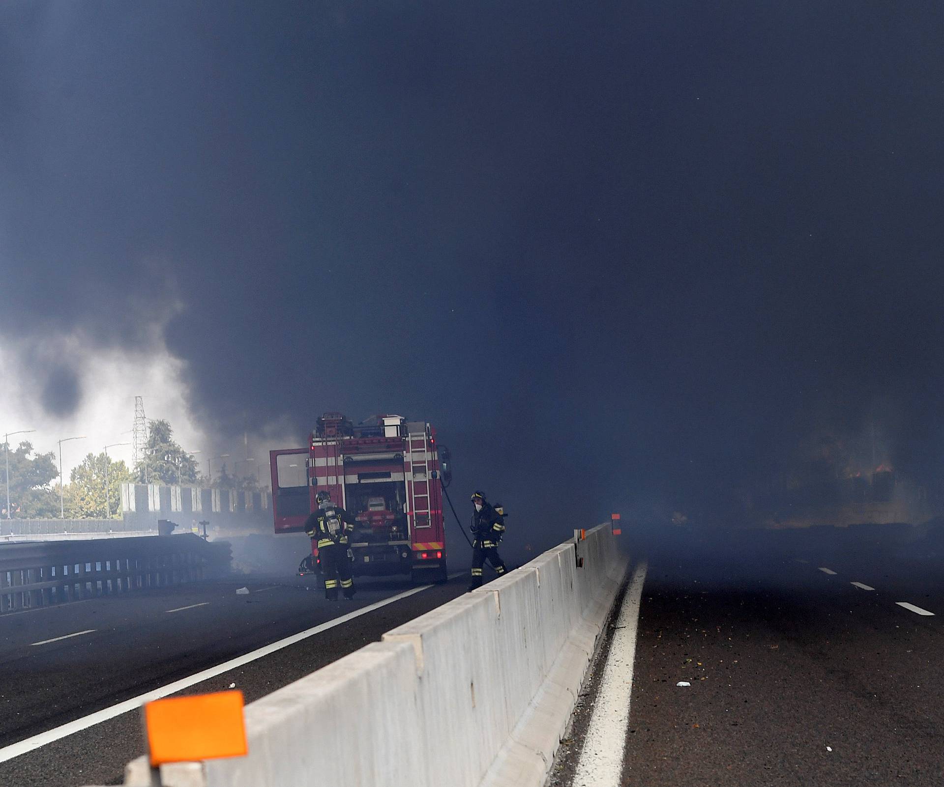 Firefighters work on the motorway after an accident caused a large explosion and fire at Borgo Panigale, on the outskirts of Bologna