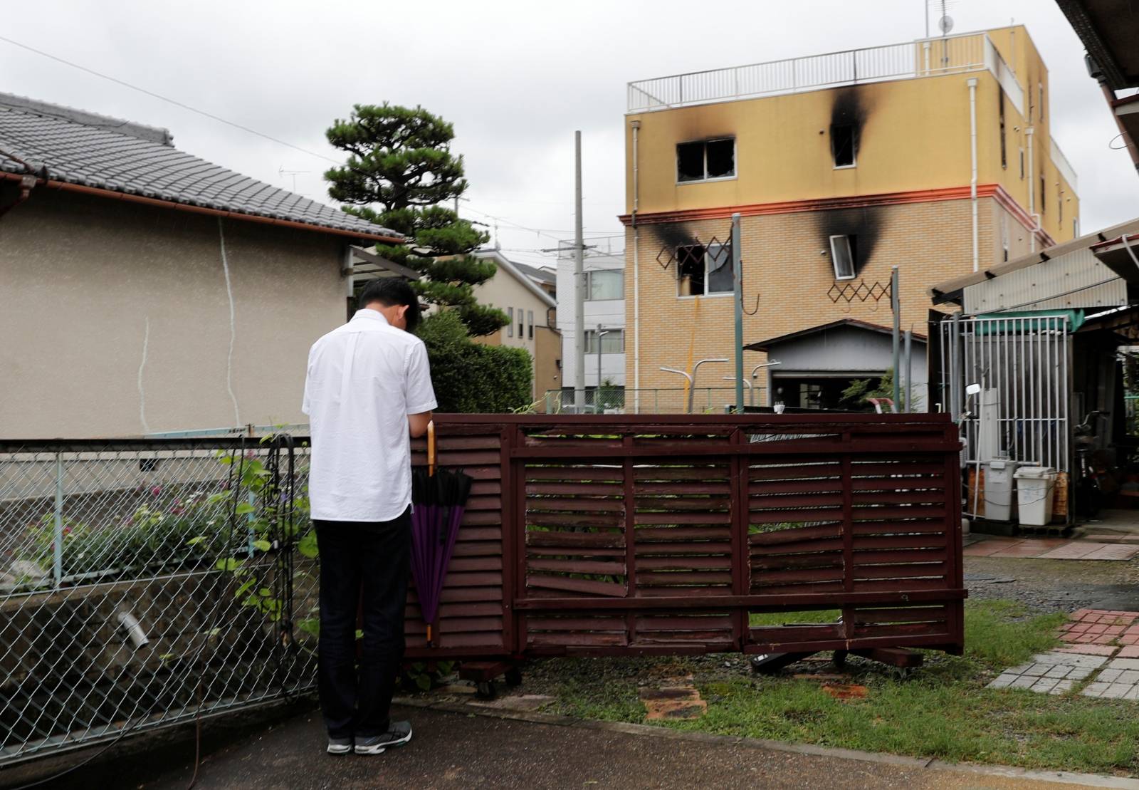 A man prays for the victims of the arson attack in front of the torched Kyoto Animation building n Kyoto