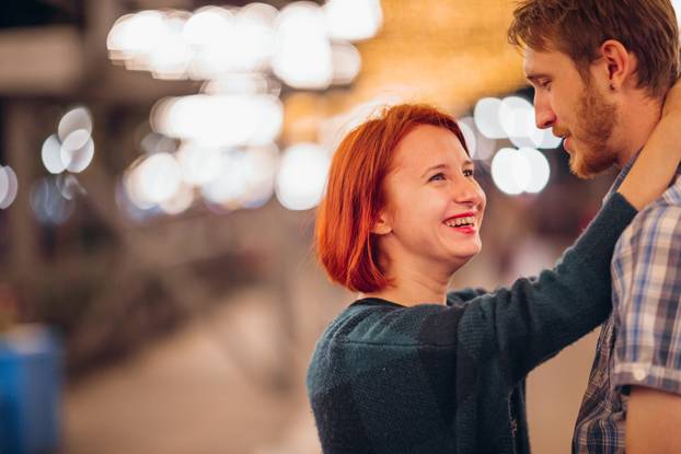HAPPY COUPLE EMBRACING IN THE ENVENING ON A LIGHT GARLANS