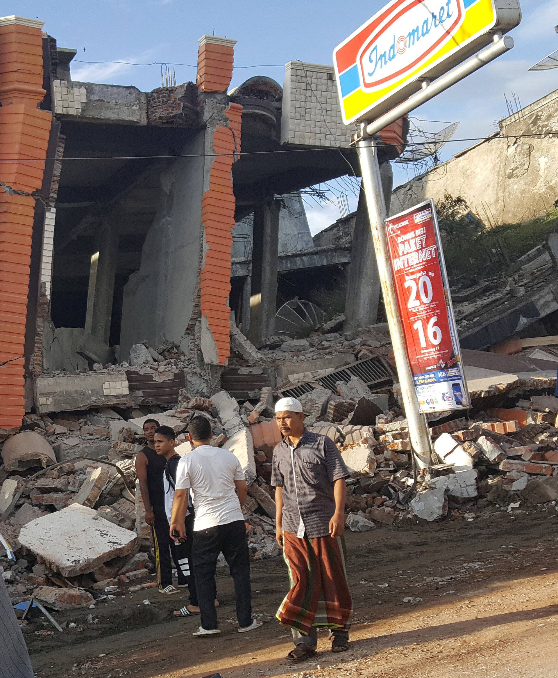 People survey the damage after dozens of buildings collapsed following a 6.4 magnitude earthquake in Ule Glee, Pidie Jaya in the northern province of Aceh, Indonesia