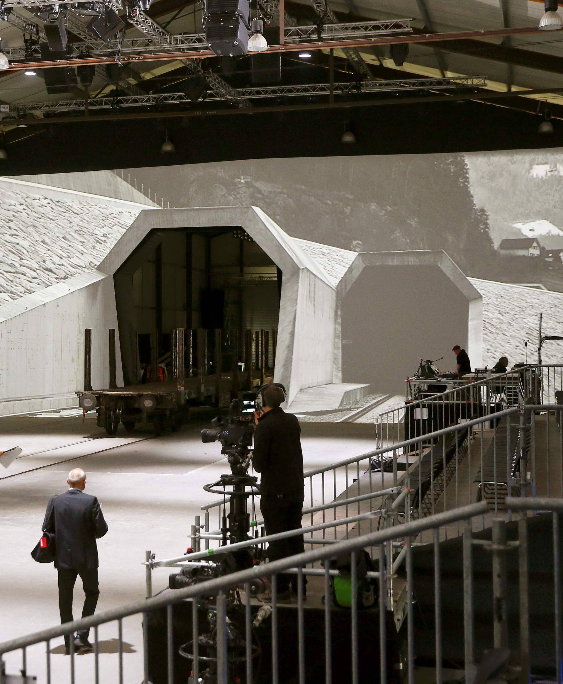 Journalists walk in front of mock gates of the NEAT Gotthard Base Tunnel inside the event hall for the upcoming opening ceremony near the town of Erstfeld