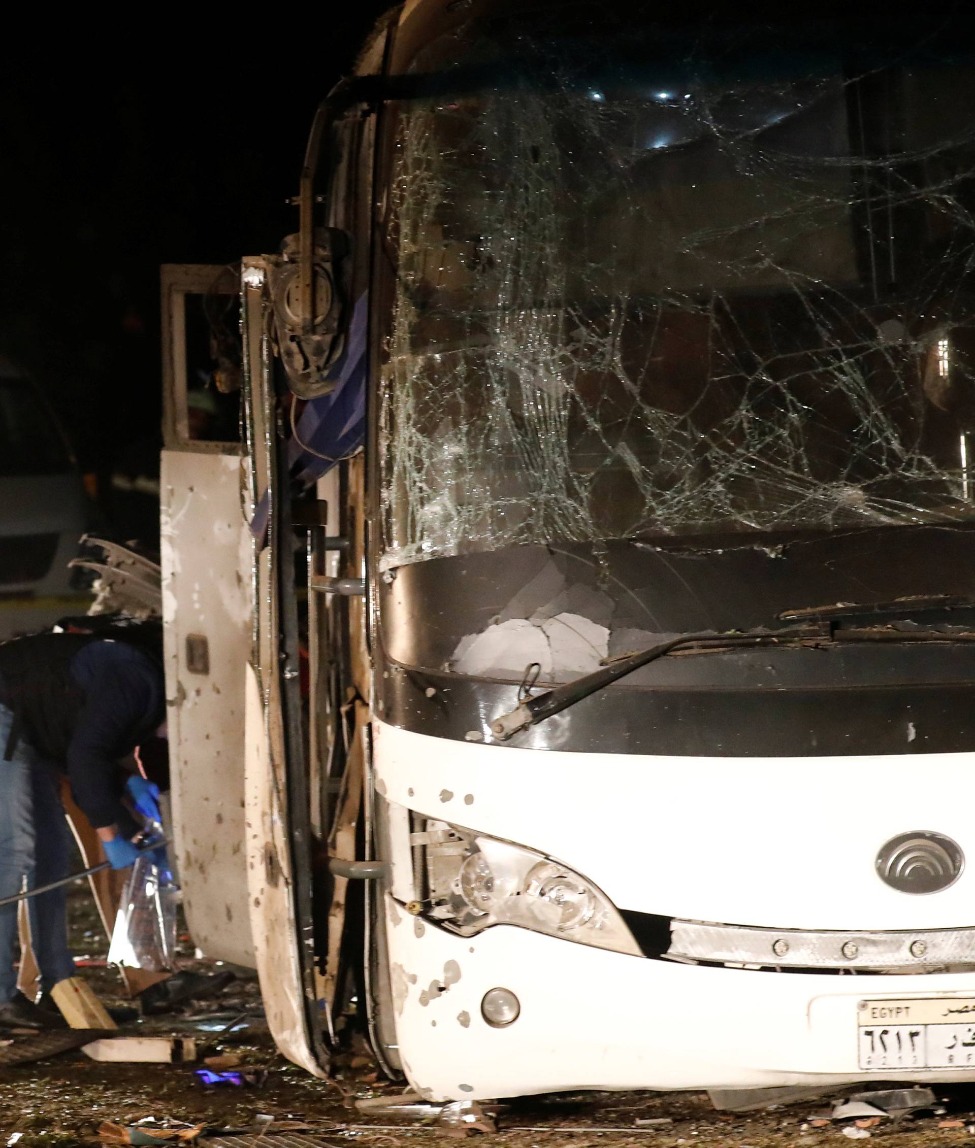 Police officers inspect a scene of a bus blast in Giza