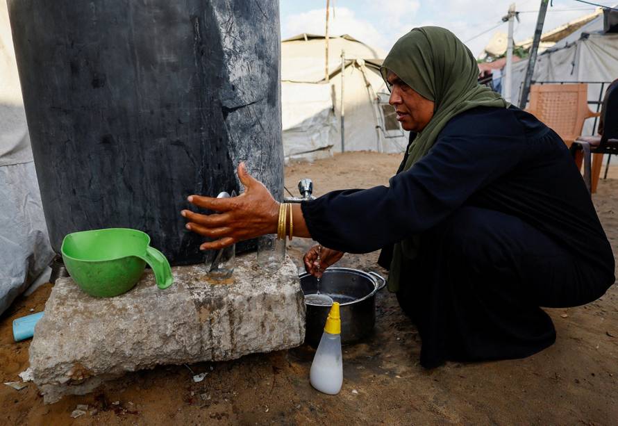A Palestinian woman collects water amid shortages in Gaza City