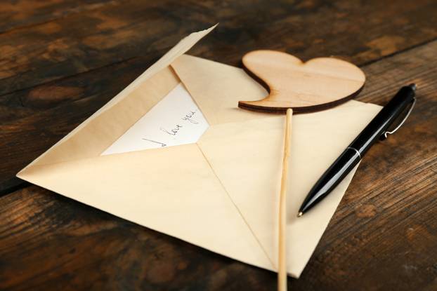Envelope with heart and pen on rustic wooden table background