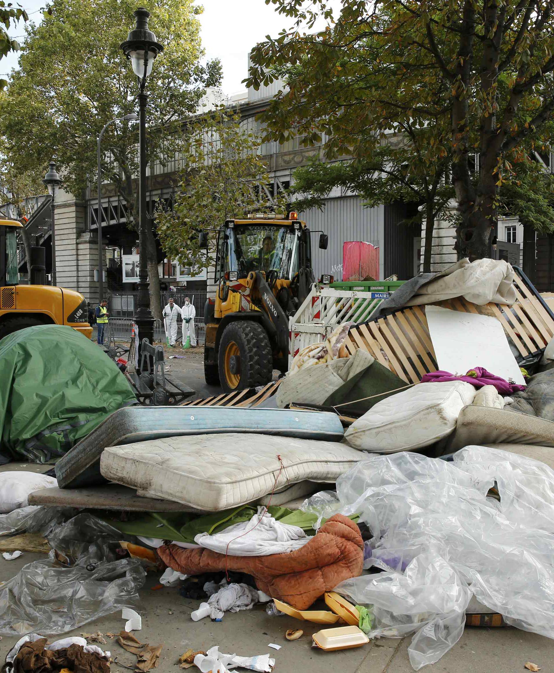 City workers remove tents and mattresses from an evacuated makeshift migrant camp near the metro stations of Jaures and Stalingrad in Paris