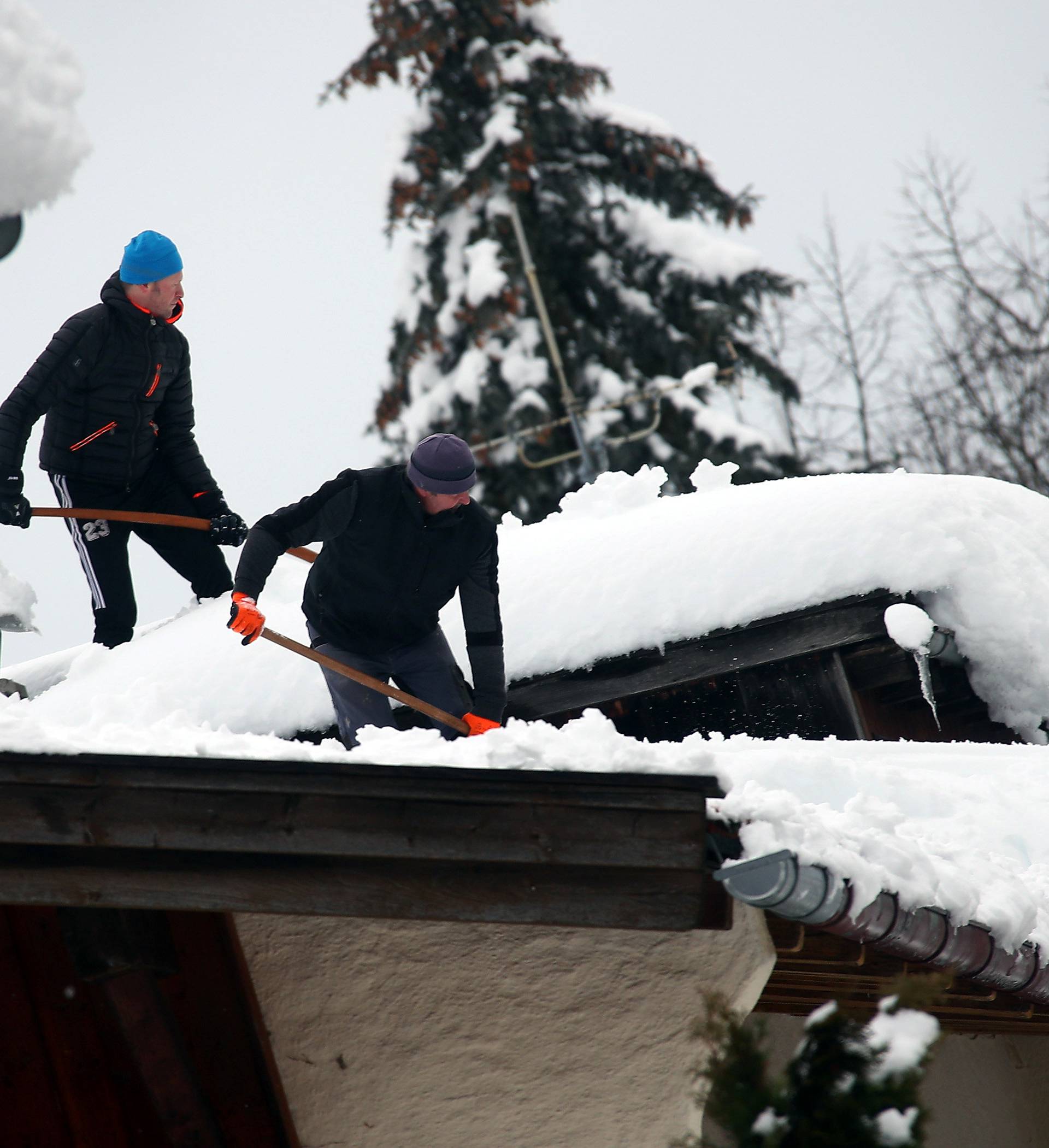 People shovel snow from the roofs of their houses after heavy snowfall in Warngau