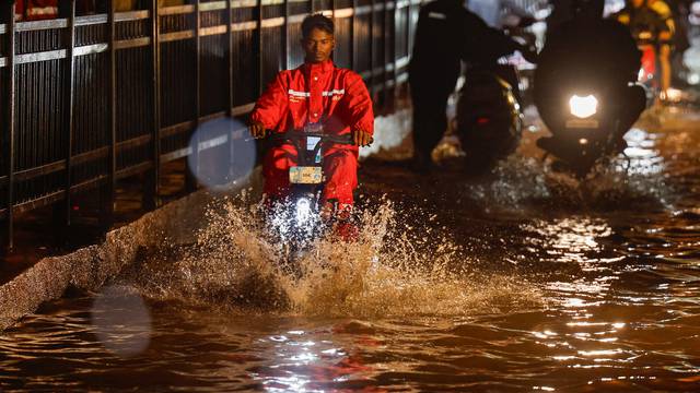 A delivery person rides an electric scooter in a waterlogged subway after heavy rains in Mumbai