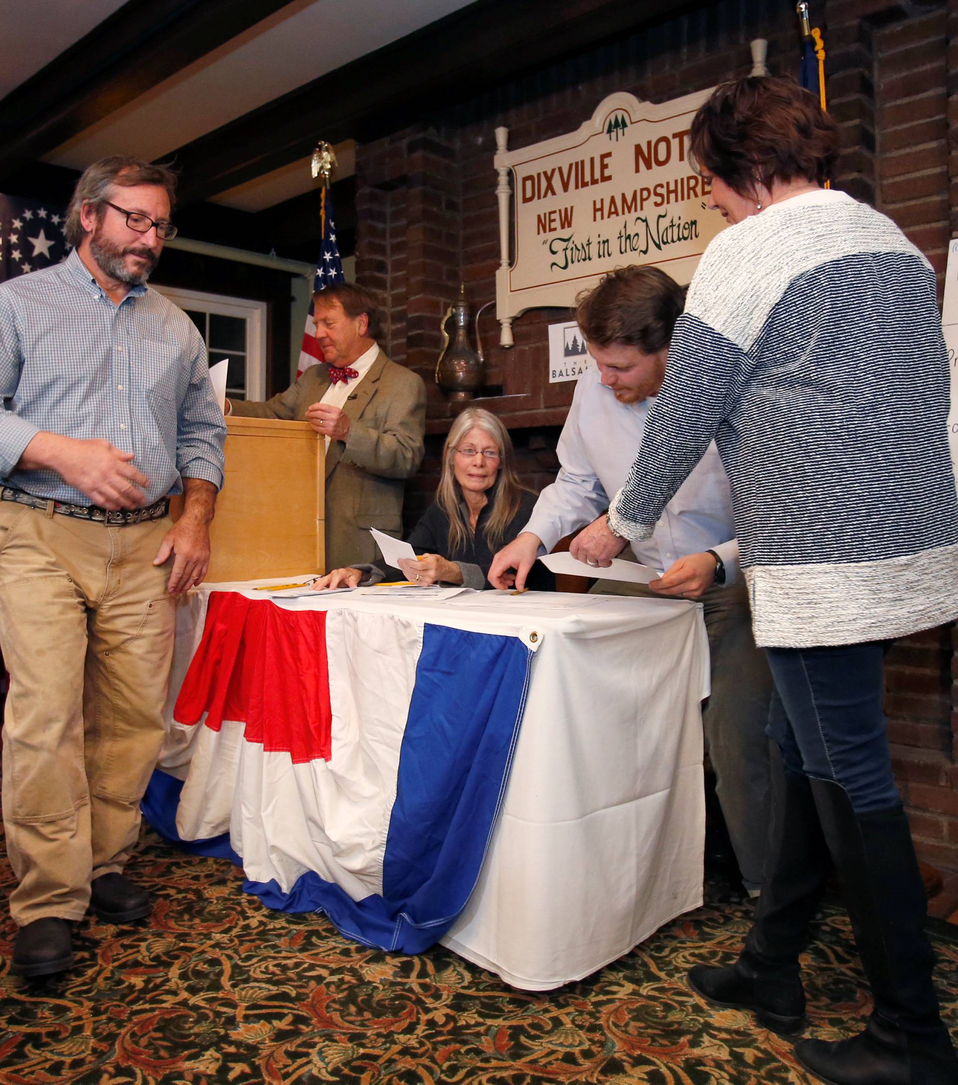 Nancy DePalma hands in her same day voter registration to Clay Smith as Russ Van Deursen becomes one of the first U.S. voters to cast a ballot in the U.S. presidential election at midnight in tiny Dixville Notch