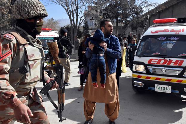 A man carries a boy as he shouts for an ambulance after gunmen attacked the Bethel Memorial Methodist Church in Quetta