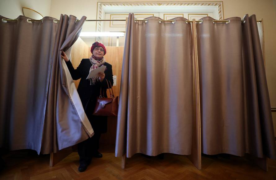 A woman walks out of a voting booth during the presidential election, inside the Russian Embassy in London
