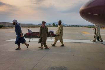 People carry an earthquake victim on a stretcher to an ambulance at an airport in Jalalabad