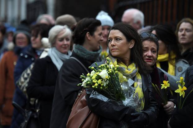 Schoolfriends bring yellow flowers to represent sunshine as they queue up to view Cranberries singer Dolores O