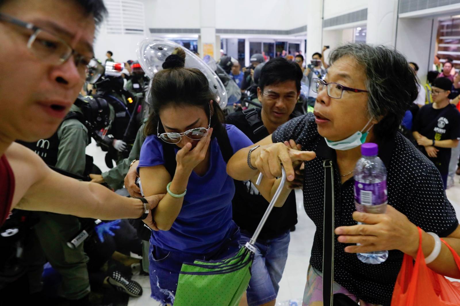 Anti-government protesters react from pepper spray as riot police despise them at a shopping mall in Tai Po, Hong Kong