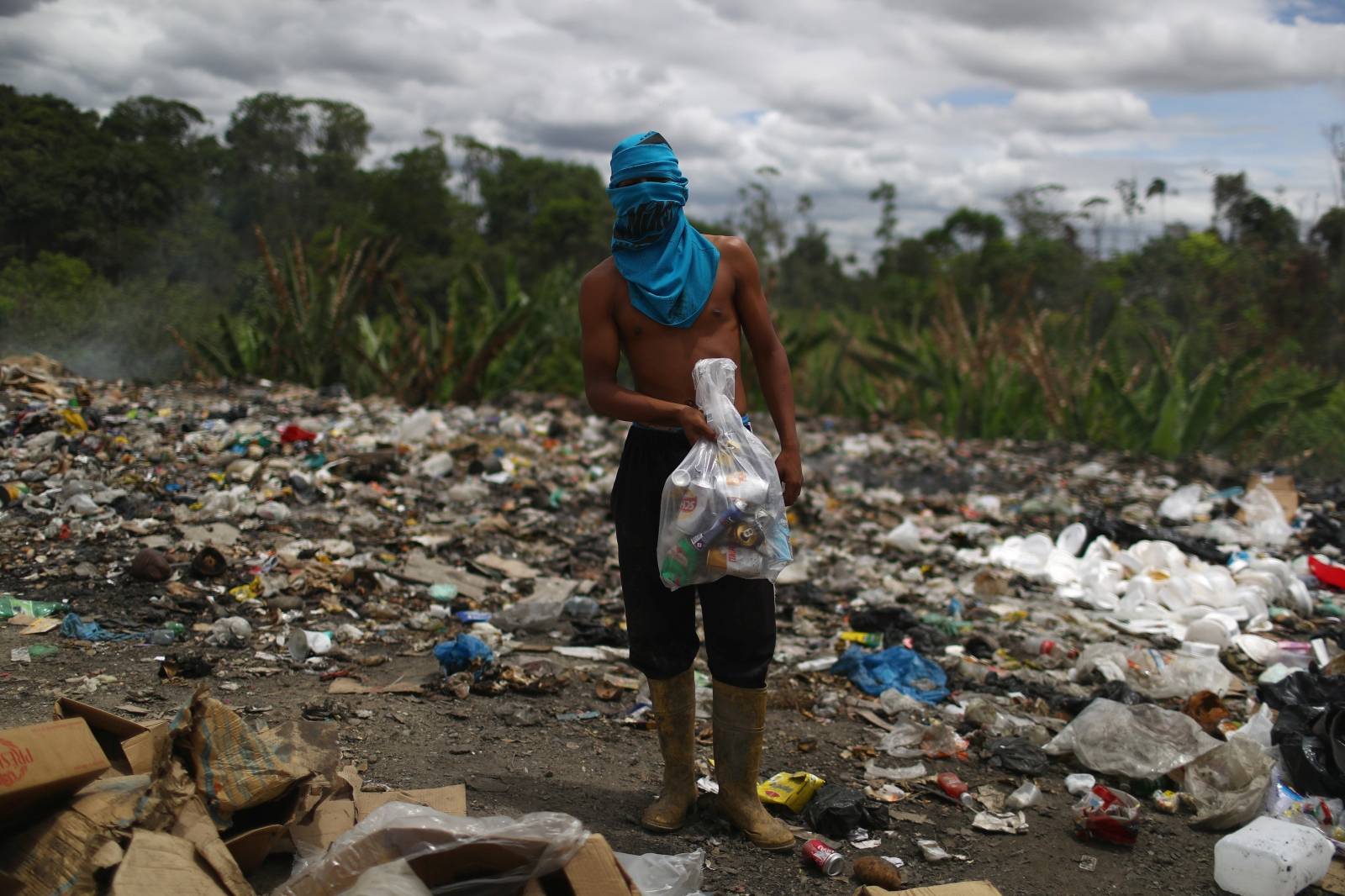 Venezuelan Luis Ortega holds a bag of cans after scraping on a garbage dump in the border city of Pacaraima