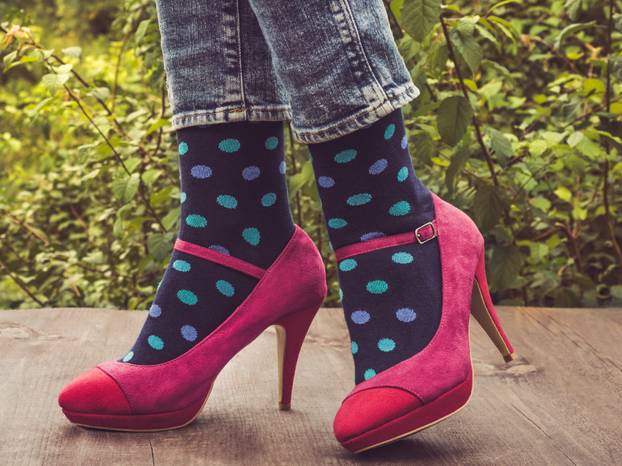 Women's legs in stylish shoes, bright, variegated, multi-colored socks