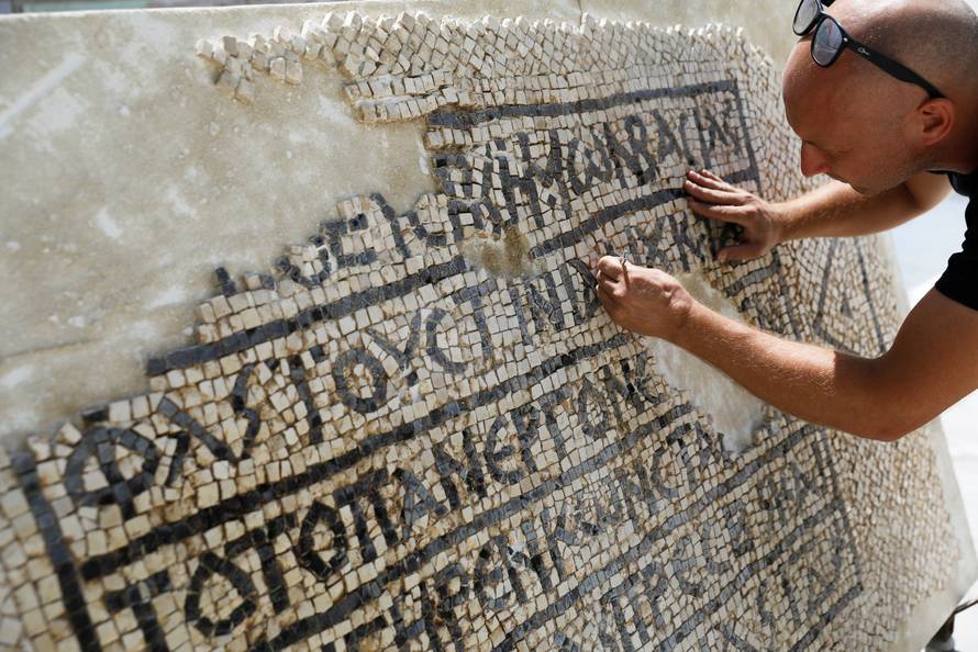 A conservationist works on a 1500-year-old mosaic floor bearing a Greek writing, discovered near Damascus Gate in Jerusalem's Old City, as it is displayed at the Rockefeller Museum in Jerusalem
