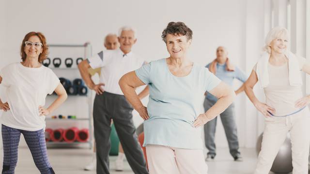 Smiling,Elderly,Woman,Holding,Hips,During,Gymnastic,Classes,For,Senior