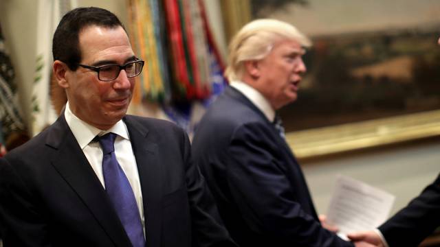 Secretary of the Treasury Steven Mnuchin stands as U.S. President Donald Trump arrives to attend a listening session with CEOs of small and community banks at the White House in Washington