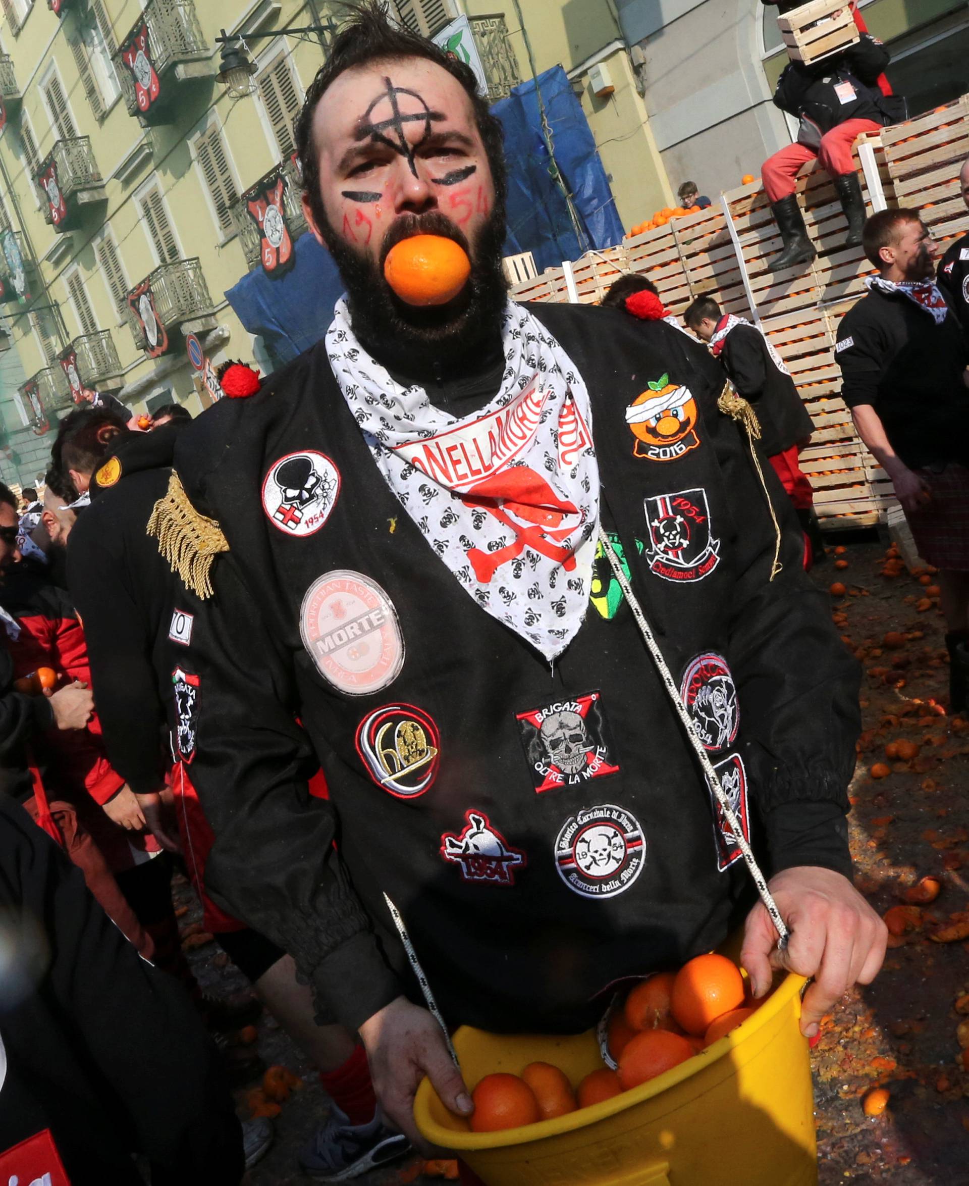 A member of a team holds an orange in his mouth during an annual carnival battle in the northern Italian town of Ivrea