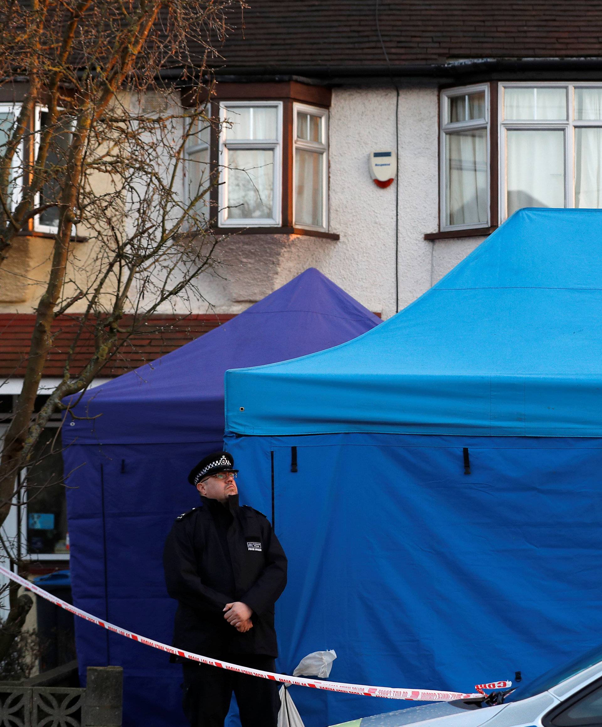 A police officer stands guard outside the home of Nikolai Glushkov in New Malden