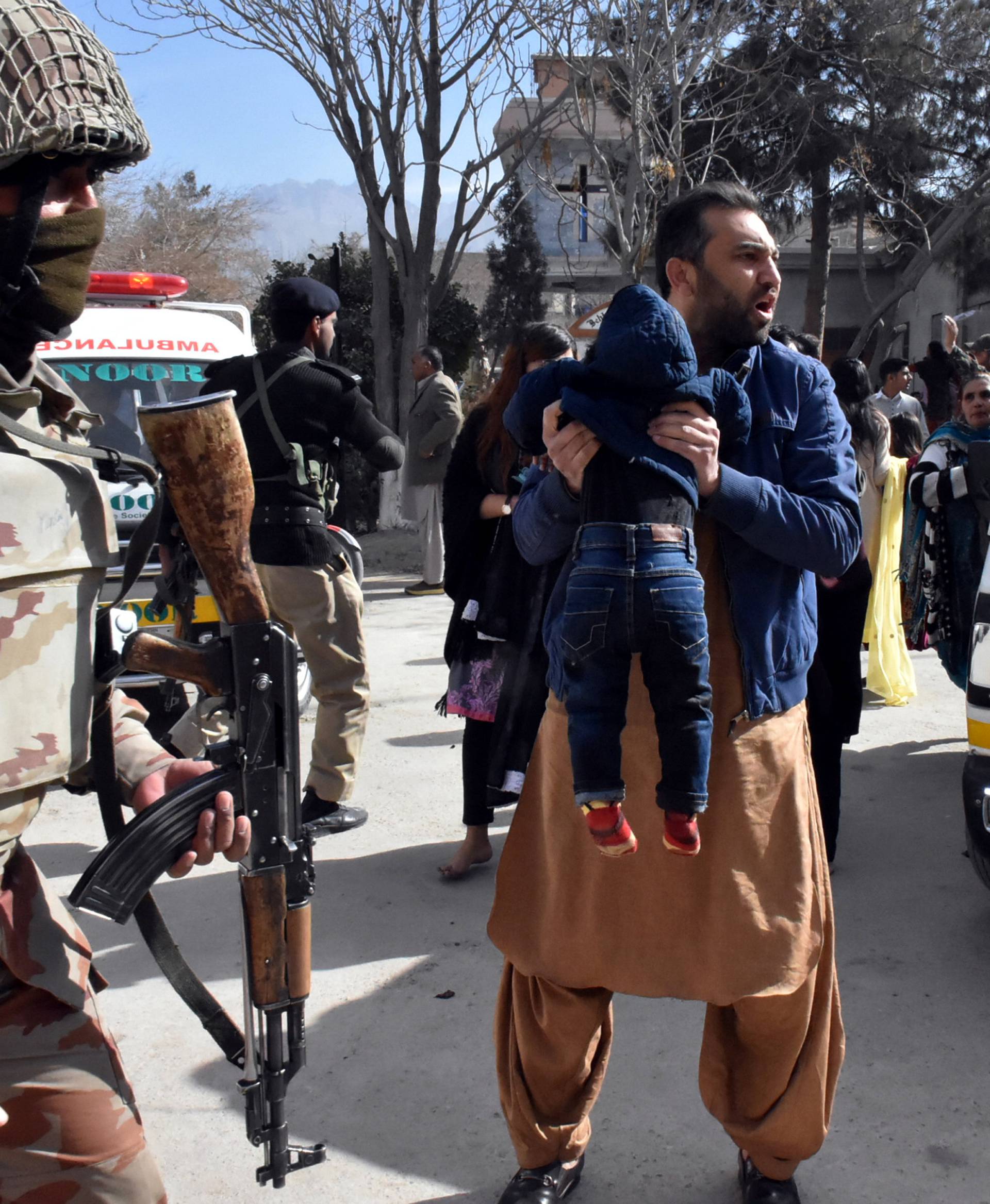 A man carries a boy as he shouts for an ambulance after gunmen attacked the Bethel Memorial Methodist Church in Quetta